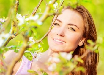 Closeup portrait of attractive young lady having fun outdoors, spring nature, apple tree blossom, sunny day, happiness concept
