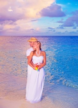 Luxury wedding on the beach,  happy romantic couple enjoying sunset on the sea, spending honeymoon vacation on Maldives islands