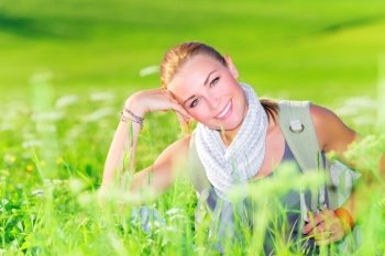 Portrait of attractive woman sitting on floral meadow, trekking along countryside, summertime travel and tourism concept