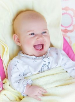 Closeup portrait of pretty newborn baby laughing, little child lying down in the bed at home, positive facial expression, happy childhood concept