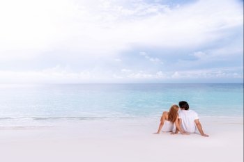 Romantic couple sitting on the beach and enjoying beautiful seaview, side view, spending time together, summer vacation concept