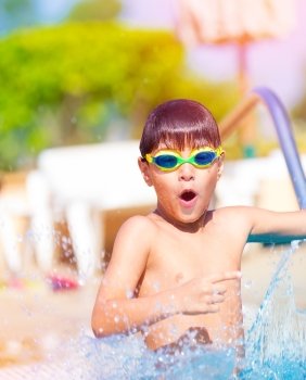 Closeup on pretty boy having fun in the pool, adorable child wearing swimming goggles, summer holidays on luxury beach resort, water sport concept