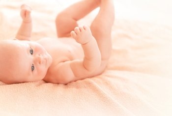 Cute newborn baby lying down on the bed at home, sweet adorable toddler, happy infant, children care, healthy lifestyle, new life concept