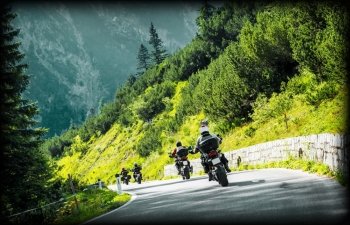 Group of moto bikers on mountainous highway, riding on curve road pass across Alpine mountains, extreme lifestyle, freedom concept