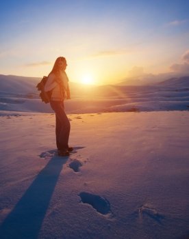 Traveler woman in the high snowy mountains enjoying beautiful sunset, active winter holidays, healthy and sportive lifestyle