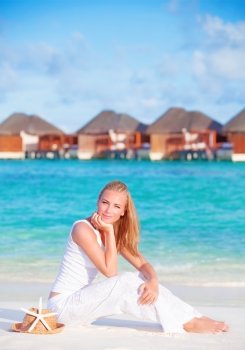 Pretty female on luxury beach resort, sitting on white clean sand and with closed eyes enjoying sunny day, summer vacation concept