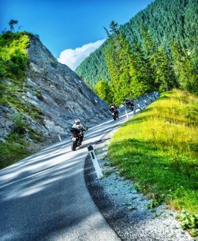 Group of bikers touring along Alpine mountains, active people enjoying extreme sport, motorcycle race, Austria, Europe