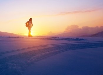 Woman enjoying beautiful sunset view from the high snowy mountain, discovering wild nature, active winter holidays