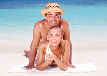 Happy couple lying down on beautiful sandy shore, having fun outdoors, spending honeymoon vacation on beach resort, love and romance concept