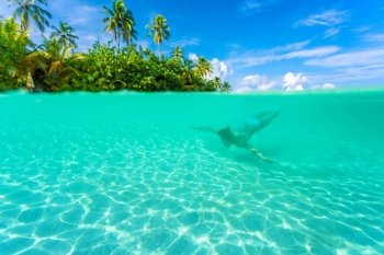 Female diving near exotic island, swimming under transparent water, relaxation on tropical resort, summer vacation concept

