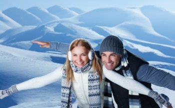 Happy couple playing outdoors in winter, imitate the flight by hands, having fun together in the snowy mountains, with pleasure spending Christmas holidays

