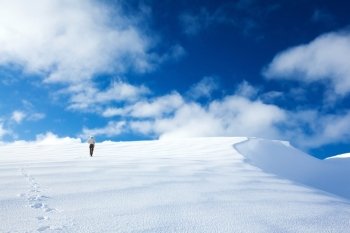 Woman traveling in the mountains in wintertime, active sportive lifestyle, walking along beautiful white snow, happy winter holidays