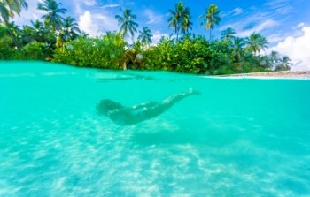 Female diving near exotic island, swimming under transparent water, relaxation on tropical resort, summer vacation concept

