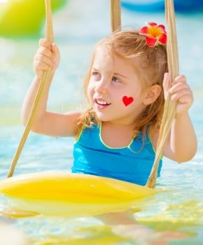 Closeup portrait of sweet little girl with red heart print on cheek having fun on water attractions, summer holiday, joy and pleasure concept
