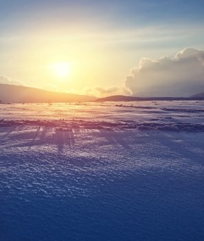 Beautiful winter landscape, bright yellow sunset light over mountains covered with clean white snow, amazing wintertime nature