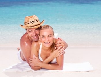 Happy couple lying down on beautiful sandy shore, having fun outdoors, spending honeymoon vacation on beach resort, love and romance concept