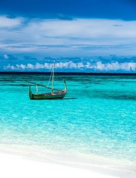 Little fishing boat in blue sea, clear transparent water and white sandy beach on luxury Maldives resort, summer vacation concept