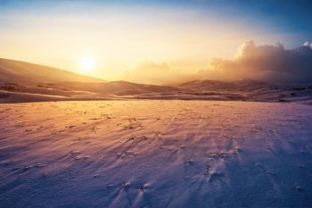 Photo of a sunset at winter snowy mountains, peaceful stunning landscape, amazing seasonal nature, cold weather in the park, beautiful sunny snow field, wintertime scene, icy lands