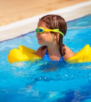Closeup portrait of happy little girl swimming in the pool, active childhood, having fun outdoors, summer holidays, floating in clear blue water