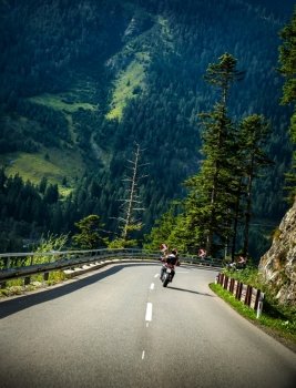Motorcyclist on curves mountainous road, Alpine mountains, active lifestyle, driving  motorbike, beautiful green nature, speed concept