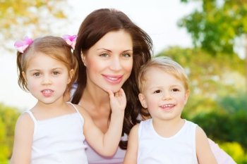 Photo of beautiful woman with two cute kids, closeup portrait of young mother with sweet daughter and lovely son outdoors, adorable children with mommy on the park in spring, happy family concept