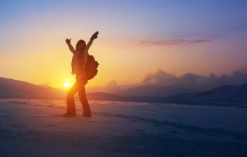 Happy joyful woman having fun outdoors, standing on the mountains with raised up hands on the mountain covered with snow, active winter holidays