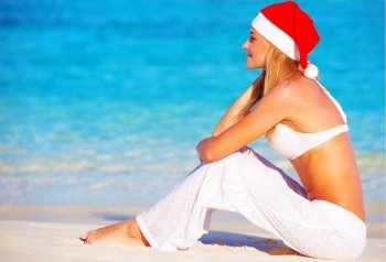 Christmas holidays on Maldives,  pretty female on the beach wearing Santa Claus hat, side view, travel and vacation concept
