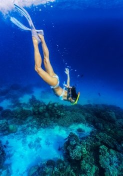Woman diving to the sea bottom, watching for beautiful marine life, people activity on Maldives, summer adventure, extreme sport