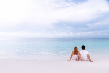 Romantic couple sitting on the beach and enjoying beautiful seaview, side view, spending time together, summer vacation concept