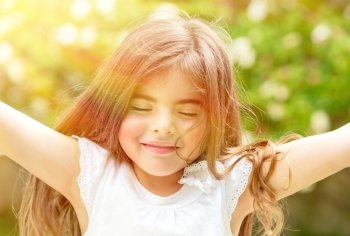 Portrait of attractive little Arabic girl with closed eyes enjoying sunny day, having fun outdoors, pleasure and happiness concept