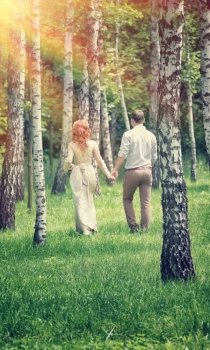 Loving couple walking between birch in the park in sunny day, back side, happy wedding day, love and romantic concept

