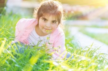 Portrait of a cute little girl having fun outdoors, adorable child  playing on fresh green grass field in bright sunny day, happy and carefree childhood