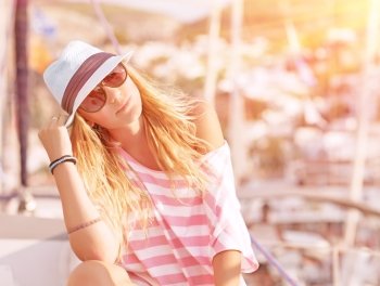 Portrait of attractive woman relaxing on luxury sailboat, enjoying mild sunset light, summer fashion and style concept
