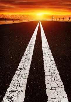 Long highway, road on sunset, red dramatic cloudy sky, two white line on dark asphalt, speed highway along desert,  freedom and travel concept