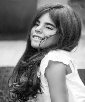 Fashion black and white photo of a beautiful little girl having fun in the park, closeup on happy face, model with long nice hair
