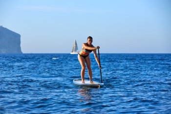SUP Stand up Surf girl with paddle in a blue ocean sea
