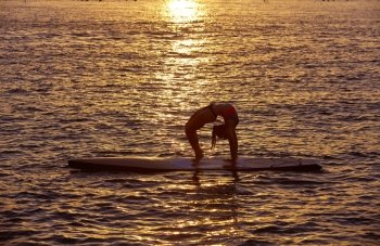 Yoga girl over SUP Stand up Surf board at the ocean sea