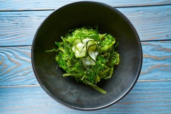 Algae salad with cucumber sesame and soya in black bowl