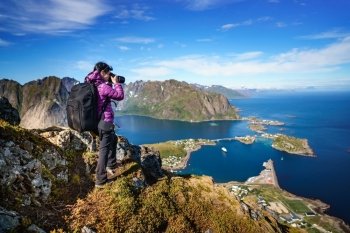 Nature photographer tourist with camera shoots while standing on top of the mountain. Beautiful Nature Norway Lofoten archipelago.