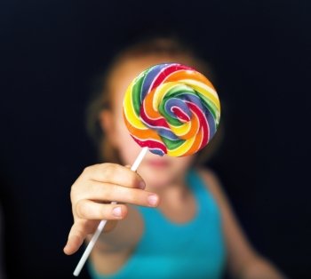 Ginger girl holding a sweet and colorful lollipop
