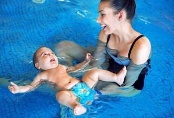 Young mother and cute baby relaxing in the swimming pool