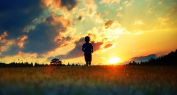 Cheerful child running towards the sunset