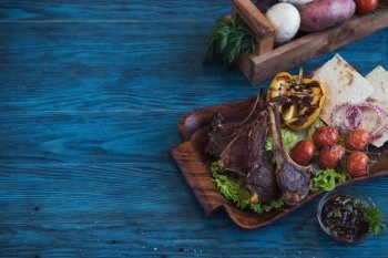 Grilled lamb meat with vegetable on a blue wooden background. Grilled lamb meat
