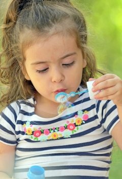Child blowing soap bubbles in nature