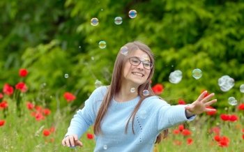 Girl Catching Soap Bubbles on spring field