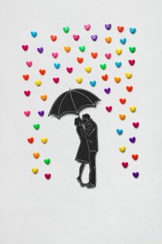 Creative valentines concept photo of a couple with umbrella and rain hearts on white background.