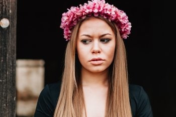 Beautiful portrait of a blonde girl with a pink wreath of flowers on her head 
