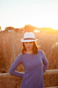 Stylish young woman with white hat in the field