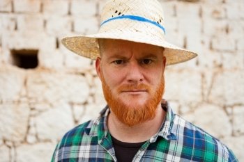 Red haired man with a straw hat in a rural enviroment