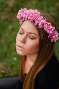 Beautiful portrait of a blonde girl with a pink crown of flowers on her head 